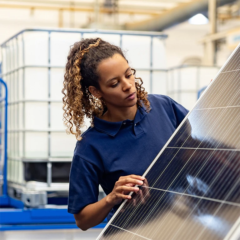 Black woman inspecting a solar panel