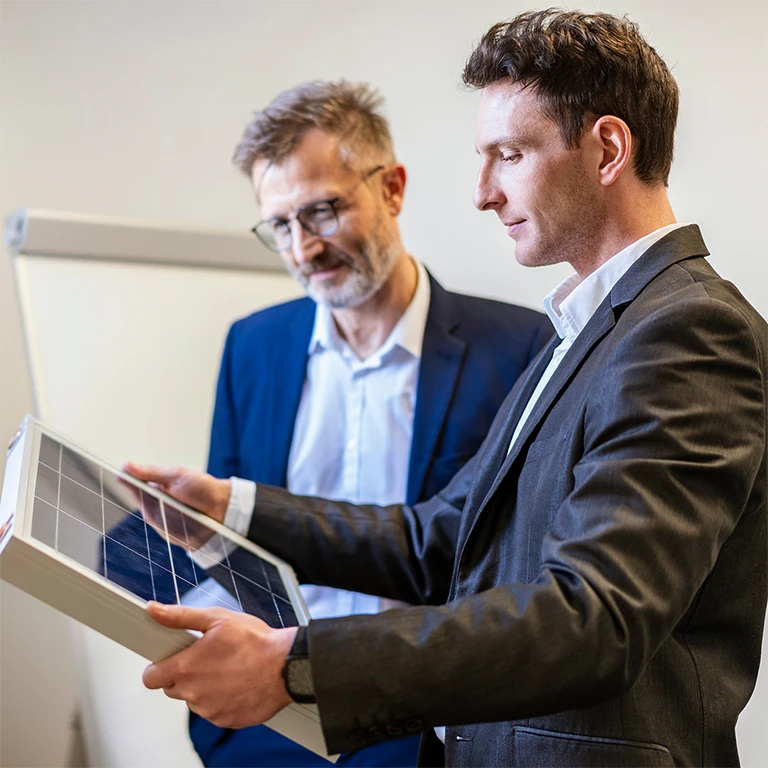 Two men in suits looking at fine piece of solar cells