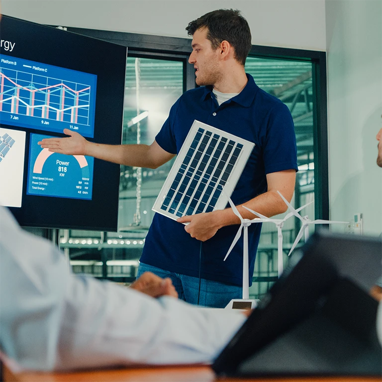 People in a meeting looking at solar cell capacity data on a large screen